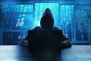 An image featuring a person wearing a hoodie representing a hacker and using his laptop